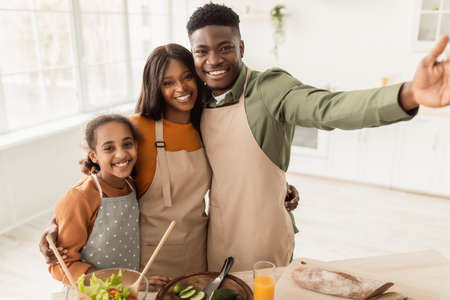 Cheerful African American Family Embracing Smiling Standing In Modern Kitchenの写真素材