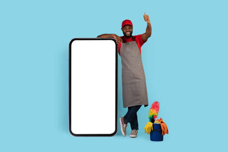 Black Cleaner Man Standing Near Big Blank Smartphone And Showing Thumb Up