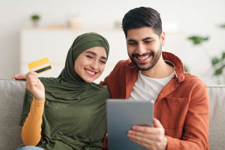 Middle Eastern Couple Shopping Online Using Digital Tablet At Homeの写真素材
