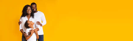 Loving black family with daughter embracing and smiling at cameraの写真素材