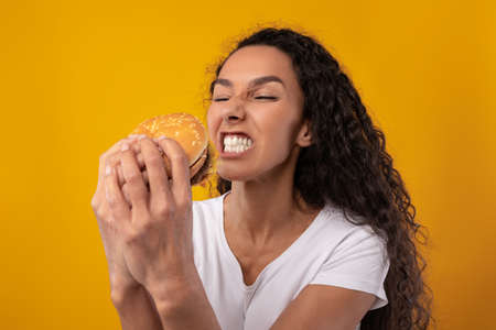 Hungry Lady Holding Burger Biting Sandwich At Studioの写真素材