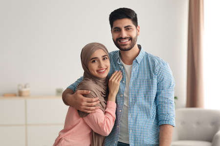 Happy Middle Eastern Wife Embracing Husband Standing At Homeの写真素材