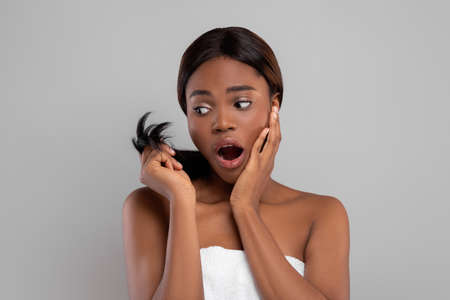 Dry Ends. Upset african american woman looking at her damaged hairの写真素材