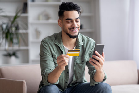 Happy Handsome Middle Eastern Guy Shopping Online With Smartphone And Credit Cardの写真素材