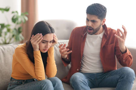 Angry Muslim Husband Yelling Wife Sitting On Sofa At Homeの写真素材