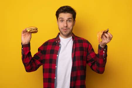 Funny Young Man Holding Burger And Slice Of Pizzaの写真素材
