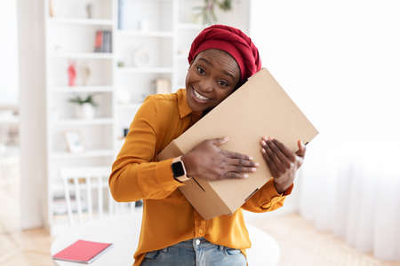 Positive african american woman got her delivery, embracing boxの写真素材