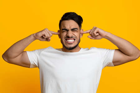 Annoyed middle eastern guy covering his earsの写真素材