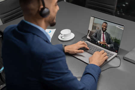 Businessman having video conference with black business partner