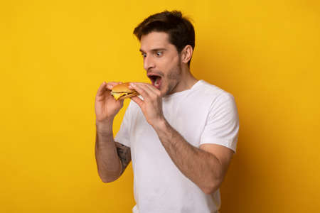 Funny Guy Holding Burger Craving Sandwich At Studioの写真素材