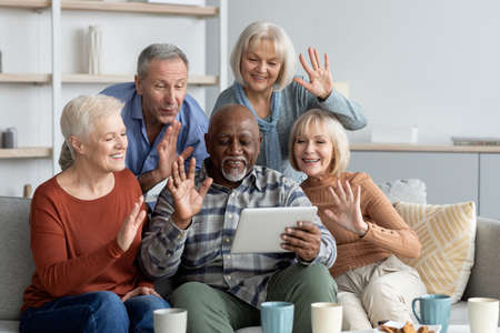 Positive multiracial senior friends having video conference, using padの写真素材