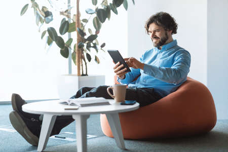 Portrait of smiling man using digital tablet at officeの写真素材