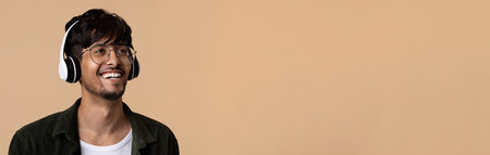 Positive indian guy using wireless headset, looking at copy space