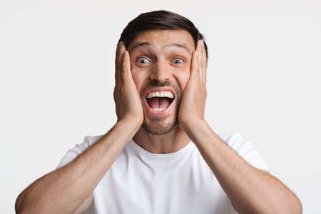 Excited Man Smiling To Camera Touching Face Over White Background