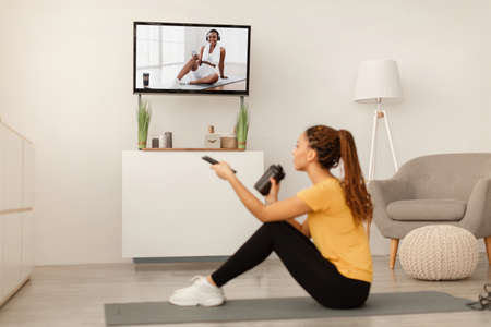 Sporty African Female Watching Sport Channel On TV At Homeの写真素材