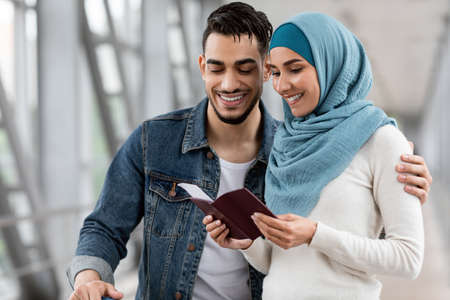 Happy Islamic Spouses Checking Passports And Tickets While Waiting Flight At Airportの写真素材