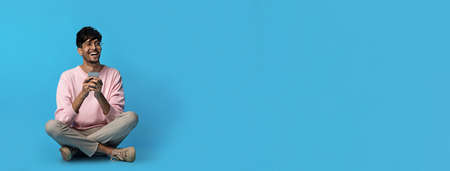 Happy middle eastern guy with smartphone looking at copy spaceの写真素材