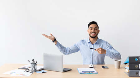 Happy Business Man Pointing Aside Sitting At Workplace