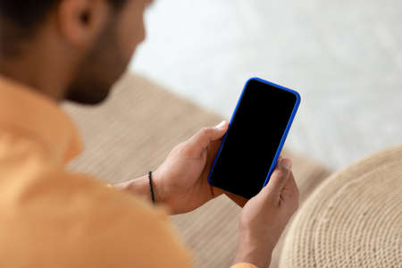 Young guy using cell with empty screen, mockup