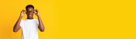 Long shot with handsome black guy in stylish eyeglasses over yellow background