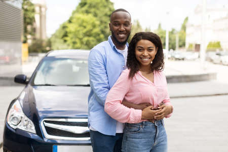 Happy black couple standing near car and huggingの写真素材