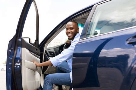 Smiling black man driving new car in the city