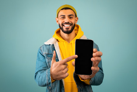 Stylish arab man pointing at smartphone with black screen