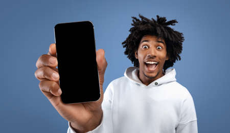 Amazed funky black guy showing cell phone with empty screenの写真素材
