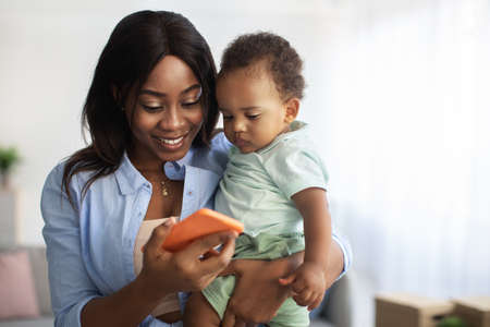 Portrait of african american mom using cellphone at home
