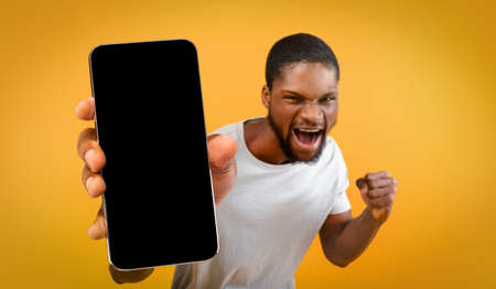 Emotional african american man showing smartphone, mockupの写真素材