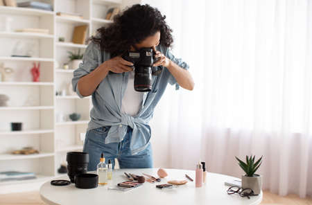 Blogger Woman With Camera Taking Photos Of Makeup Products Indoorsの写真素材