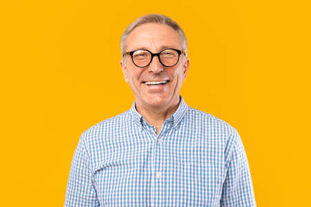 Portrait of smiling mature man in glasses posing at studio