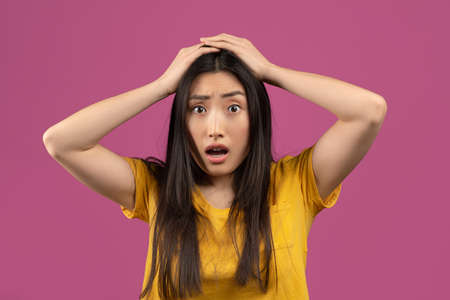 Unbelievable news. Shocked asian woman touching her head, cannot believe amazing offer or sale,...