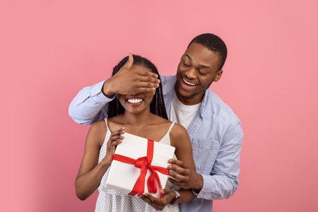 Happy black man making surprise for his lady covering eyesの写真素材