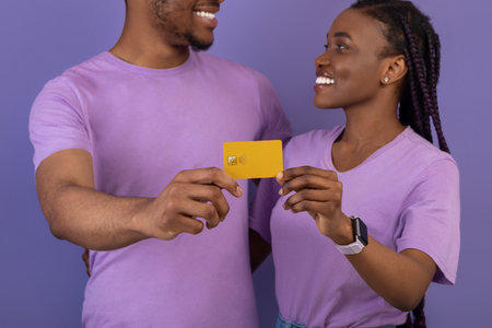 Happy black couple hugging and holding credit card