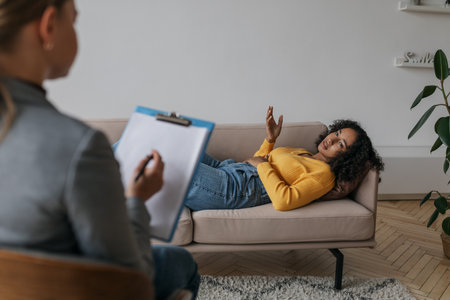 Psychotherapist giving consultation to stressed black female patient, having therapy session at officeの写真素材