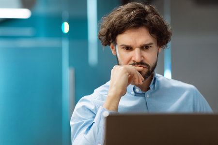 Focused man using laptop sitting at desk in office