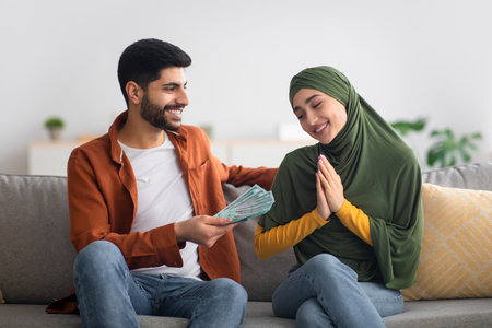 Middle Eastern Husband Giving Money To Wife Sitting At Homeの写真素材