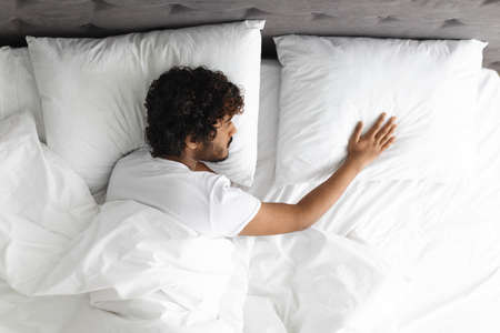 Top view of lonely guy touching pillow next to himの写真素材
