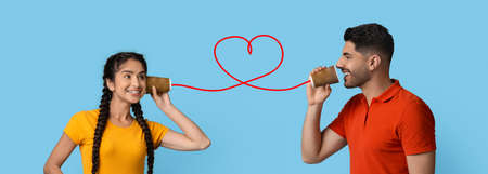 Middle eastern guy sending romantic message to girlfriend through paper cup phoneの写真素材