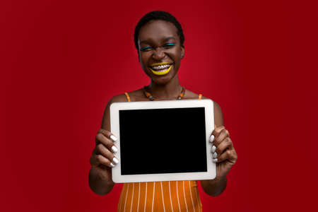 Happy stylish african american woman showing tablet with blank screen