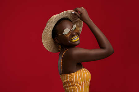 Cool black woman in summer outfit posing on red