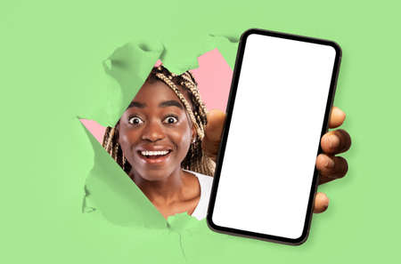 Black lady showing white empty smartphone screen through torn paper