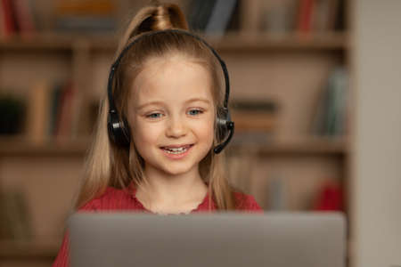 Schoolgirl Video Calling Wearing Headset Talking To Laptop At Home