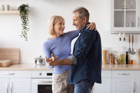 Loving senior couple enjoying time together in kitchen, dancingの写真素材