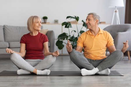 Happy elderly couple meditating together at homeの写真素材