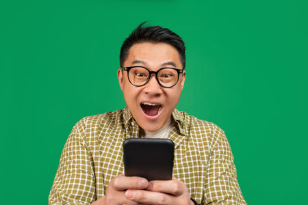 Overjoyed mature asian man in glasses looking at smartphone in shock, amazed at promo sale or huge...