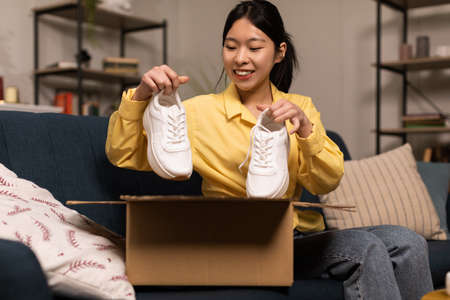 Happy Asian woman unpacking parcel after online shopping