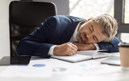 Overwork Concept. Exhausted mature businessman sleeping at workplace in modern office