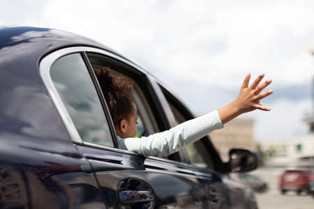 African Girl Putting Arm Out Of Car Window In City